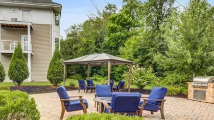 Enjoy the outdoor lounge at Oak Enclave, featuring a shaded pergola, comfortable seating, and a cozy fire pit, perfect for socializing or unwinding in a serene setting.