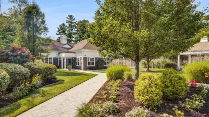 A beautifully maintained walkway with lush greenery and vibrant landscaping welcomes residents and guests to the leasing office at Oak Enclave Luxury Apartments.
