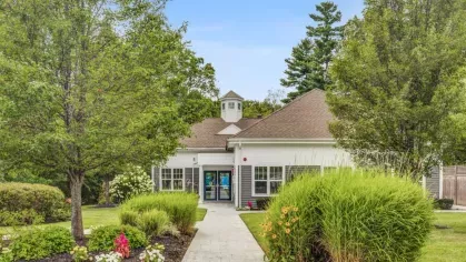 The modern clubhouse entrance at Oak Enclave Luxury Apartments showcases elegant architecture, well-kept landscaping, and a welcoming atmosphere for residents.