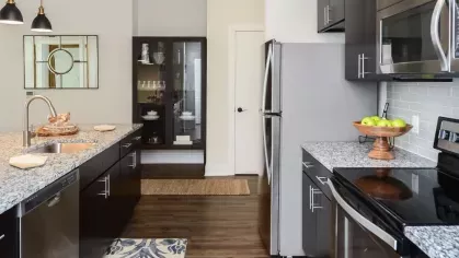 Spacious galley kitchen featuring sleek black cabinets, stainless steel appliances, and granite countertops with ample workspace.