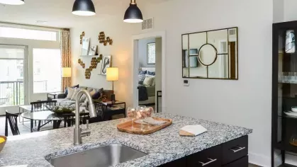 Open-concept kitchen and living area with granite countertops, black cabinetry, and elegant pendant lights adding a touch of sophistication.