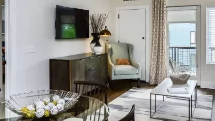 Bright living room with a comfortable seating area, glass dining table, and access to a private balcony with natural light.