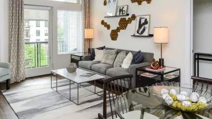 Contemporary living room featuring a gray sofa, modern wall art, and large windows leading to a private balcony with natural light.
