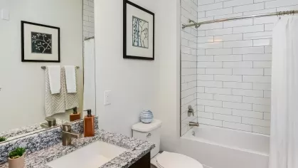Sleek bathroom featuring granite countertops, white subway tile shower, and elegant decor at Riverworks Luxury Apartments.