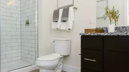 Contemporary bathroom with a glass-enclosed shower, granite vanity, and modern accents at Riverworks Luxury Apartments.