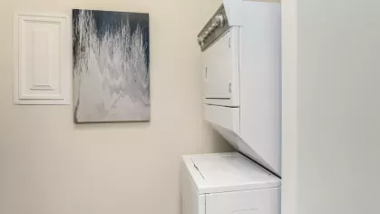 In-unit laundry room with a stacked washer and dryer, offering convenience at Riverworks Luxury Apartments.