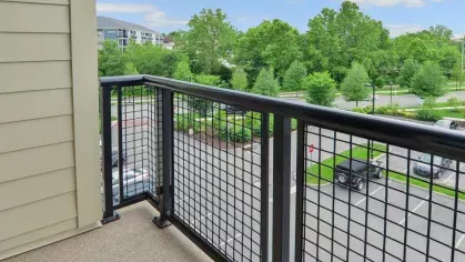 Private balcony with metal railing and picturesque views of the lush greenery at Riverworks Luxury Apartments.