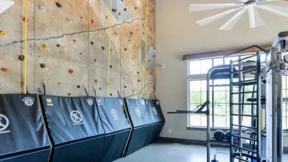 "Indoor rock climbing wall at Riverworks Luxury Apartments, featuring padded safety mats and a modern fitness area with natural light."