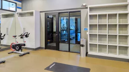 "Yoga and spin studio at Riverworks Luxury Apartments with stationary bikes, storage cubbies, and a glass door leading to the main fitness center."