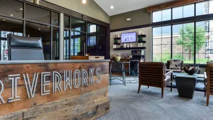 "Stylish lobby at Riverworks Luxury Apartments with a rustic wood reception desk and comfortable seating in a bright, modern setting."