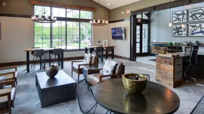 "Cozy seating area in the Riverworks Luxury Apartments lounge with a mix of modern and rustic design elements and views of the landscaped grounds."