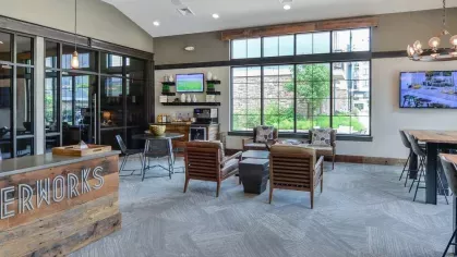 Modern lounge area at Riverworks Luxury Apartments featuring rustic wood decor, comfortable seating, and large windows with natural light.