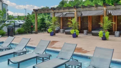 Relaxing poolside seating with lounge chairs and shaded cabanas at Riverworks Luxury Apartments.