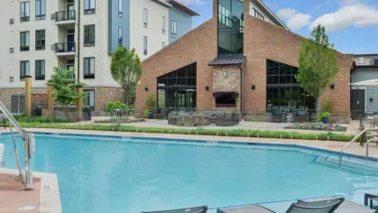 Resort-style pool with lounge chairs and a view of Riverworks Luxury Apartments’ modern clubhouse and amenities.