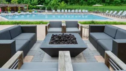 Inviting poolside fire pit area with modern seating and views of the resort-style pool at Riverworks Luxury Apartments.