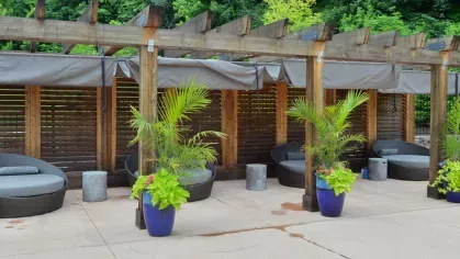Private poolside cabanas with natural wood pergolas and lush landscaping, providing shaded relaxation spaces at Riverworks Luxury Apartments.