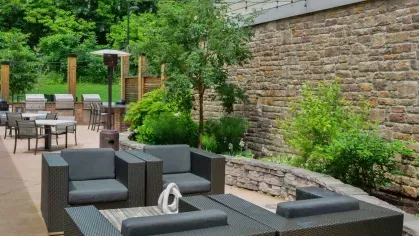 Cozy outdoor seating area with modern wicker furniture and decorative landscaping, providing a tranquil retreat at Riverworks Luxury Apartments.