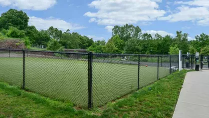 Spacious fenced dog park surrounded by lush greenery, ideal for Riverworks residents and their furry friends.