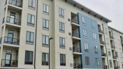 Exterior view of Riverworks Luxury Apartments' modern building design, featuring private balconies and a blend of stone and siding finishes.