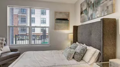 A stylish bedroom at The Royal Belmont Luxury Apartments featuring modern decor, natural light from large windows, and a cozy, plush bed.