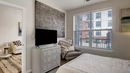 A stylish bedroom at The Royal Belmont Luxury Apartments featuring modern decor, natural light from large windows, and a cozy, plush bed.