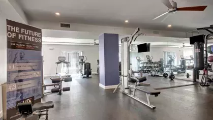 A spacious fitness center equipped with cardio machines, strength training equipment, and a mirrored wall for a complete workout experience.