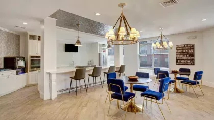 A communal kitchen with bar seating and adjacent tables, perfect for hosting and socializing in a modern, upscale environment.