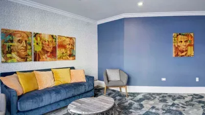A vibrant resident lounge featuring colorful artwork, a plush sofa, and cozy armchairs for a relaxed setting.