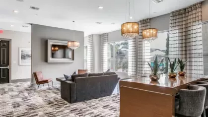 A well-lit lounge area with cozy seating, modern chandeliers, and large windows allowing natural light to fill the space.