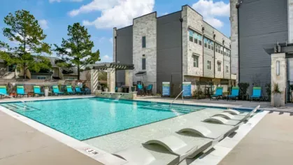A resort-style pool area featuring in-water lounge chairs, shaded seating, and a beautifully designed courtyard.