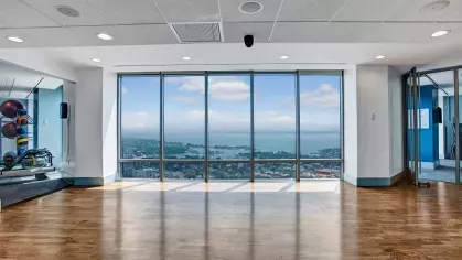 Bright yoga and exercise room with floor-to-ceiling windows showcasing a panoramic cityscape.