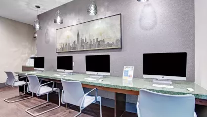 State-of-the-art business center with a row of iMac computers, ergonomic chairs, and modern lighting fixtures.