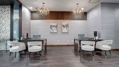 The modern leasing office at Skyline New Rochelle, featuring chic chandeliers, sleek workstations, and comfortable seating.