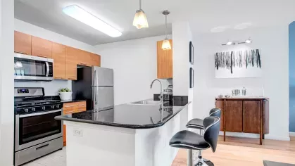 A sleek kitchen with stainless steel appliances, wooden cabinetry, and a spacious island counter perfect for meal preparation or casual dining.