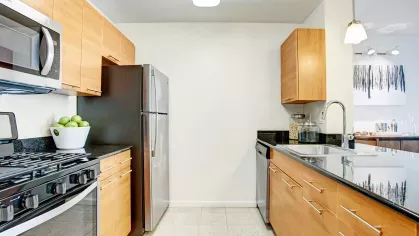 A sleek kitchen with stainless steel appliances, wooden cabinetry, and a spacious island counter perfect for meal preparation or casual dining.