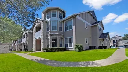 Charming apartment building with unique bay windows, surrounded by vibrant green lawns.