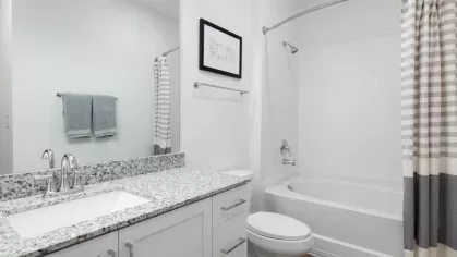 A spa-inspired bathroom with a granite vanity, white subway tile shower, and soft neutral decor, offering a sleek and modern design.