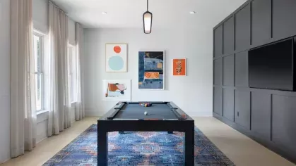 A stylish game room at Vista At Town Green, featuring a sleek black pool table, modern wall paneling, and contemporary artwork for a fun and inviting recreational space.