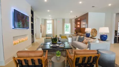 A contemporary community living space with plush sofas, a wall-mounted TV, a fireplace, and stylish decor elements, offering a comfortable area for socializing.