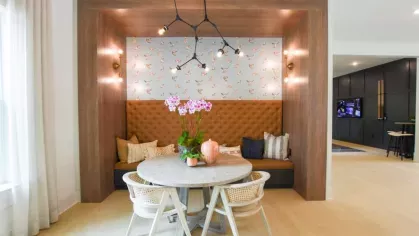 A stylish dining nook in the resident clubhouse with a tufted banquette, patterned wallpaper, and modern light fixtures, creating a cozy and inviting atmosphere.