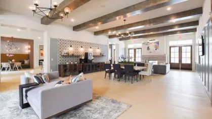 A grand clubhouse with exposed ceiling beams, an elegant chandelier, a fireplace, and multiple seating areas, providing residents with a luxurious communal space.