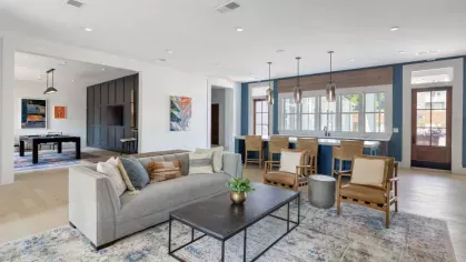 A stylish resident lounge at Vista At Town Green Luxury Apartments, featuring modern furnishings, a cozy seating area, and a sleek open kitchen with pendant lighting.