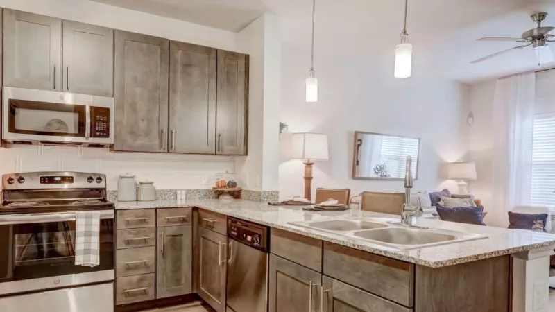 Upscale kitchen with stainless steel appliances, granite countertops, and pendant lighting at The Emerson at Forney Luxury Apartments.