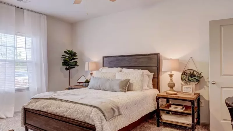 Spacious master bedroom with elegant decor, plush carpeting, and large windows at The Emerson at Forney Luxury Apartments.