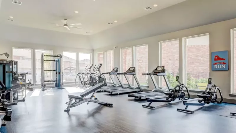 State-of-the-art fitness center at The Emerson at Forney featuring cardio machines, strength training equipment, and natural light.