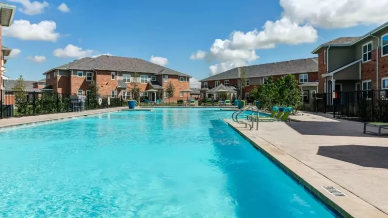 Expansive pool area with crystal-clear water and poolside seating at The Emerson at Forney Luxury Apartments, perfect for relaxation.