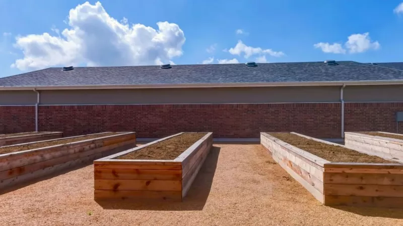 Raised garden beds in a well-maintained community garden space at The Emerson at Forney Luxury Apartments.