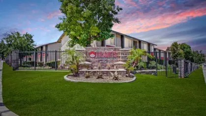 The Heights at Grand Terrace sign sits in front of a well-maintained apartment complex with lush landscaping and a vibrant sunset sky.