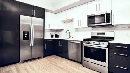 Sleek kitchen design with stainless steel refrigerator, gas stove, and a marble backsplash, offering a contemporary and functional space at The Linden.