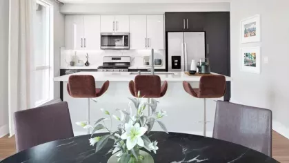 Dining area with a black marble table and upholstered chairs, seamlessly connected to the kitchen with a stylish breakfast bar at The Linden.